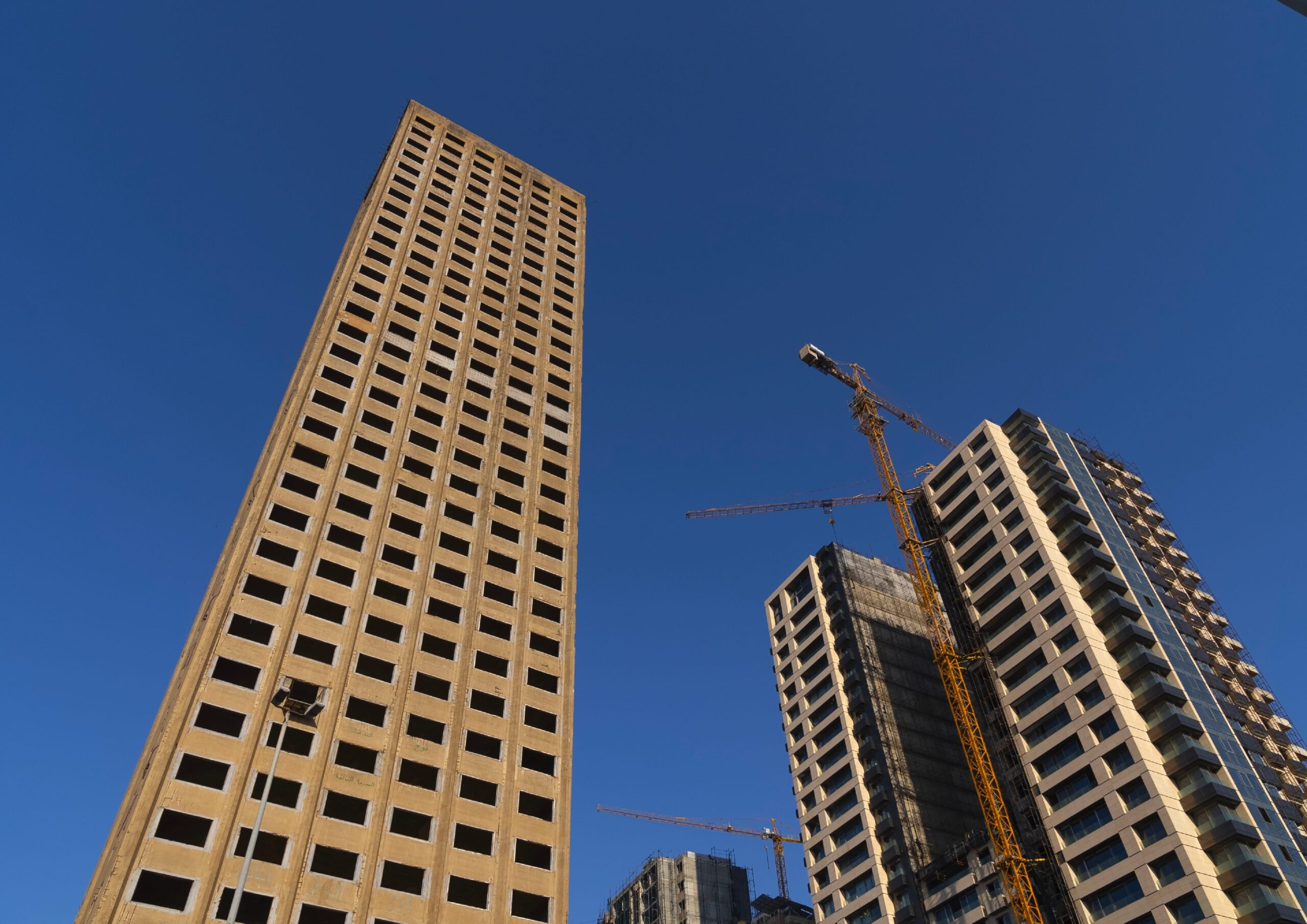 A tall brown building and another building next to it with a crane