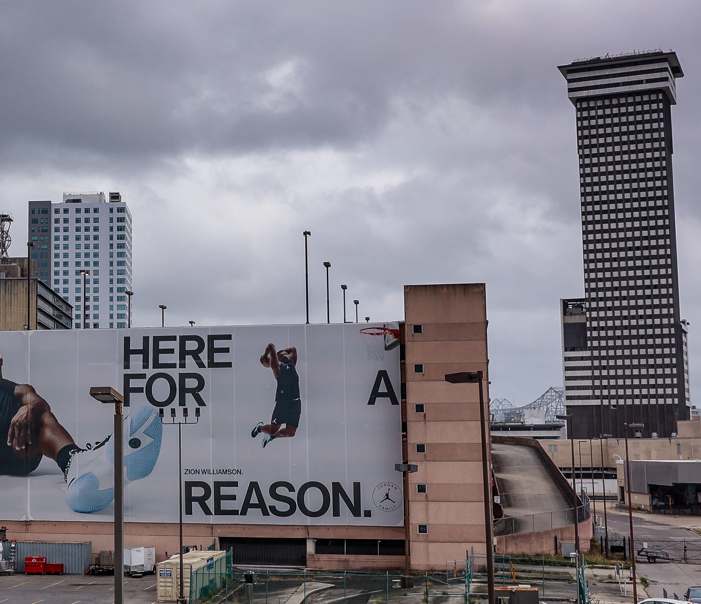 A billboard reding "Here for a reason" in front of a tall black building with square windows