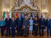 Een groep Europese en Oekraïense ministers poseert voor een foto tijdens de Weimar+ bijeenkomst in het Franse ministerie van Buitenlandse Zaken in Parijs op 12 februari 2025. De bijeenkomst richtte zich op de rol van Europese landen in de onderhandelingen over de toekomst van Oekraïne. Op de achtergrond zijn vlaggen van verschillende Europese landen te zien in een rijkelijk versierde zaal.