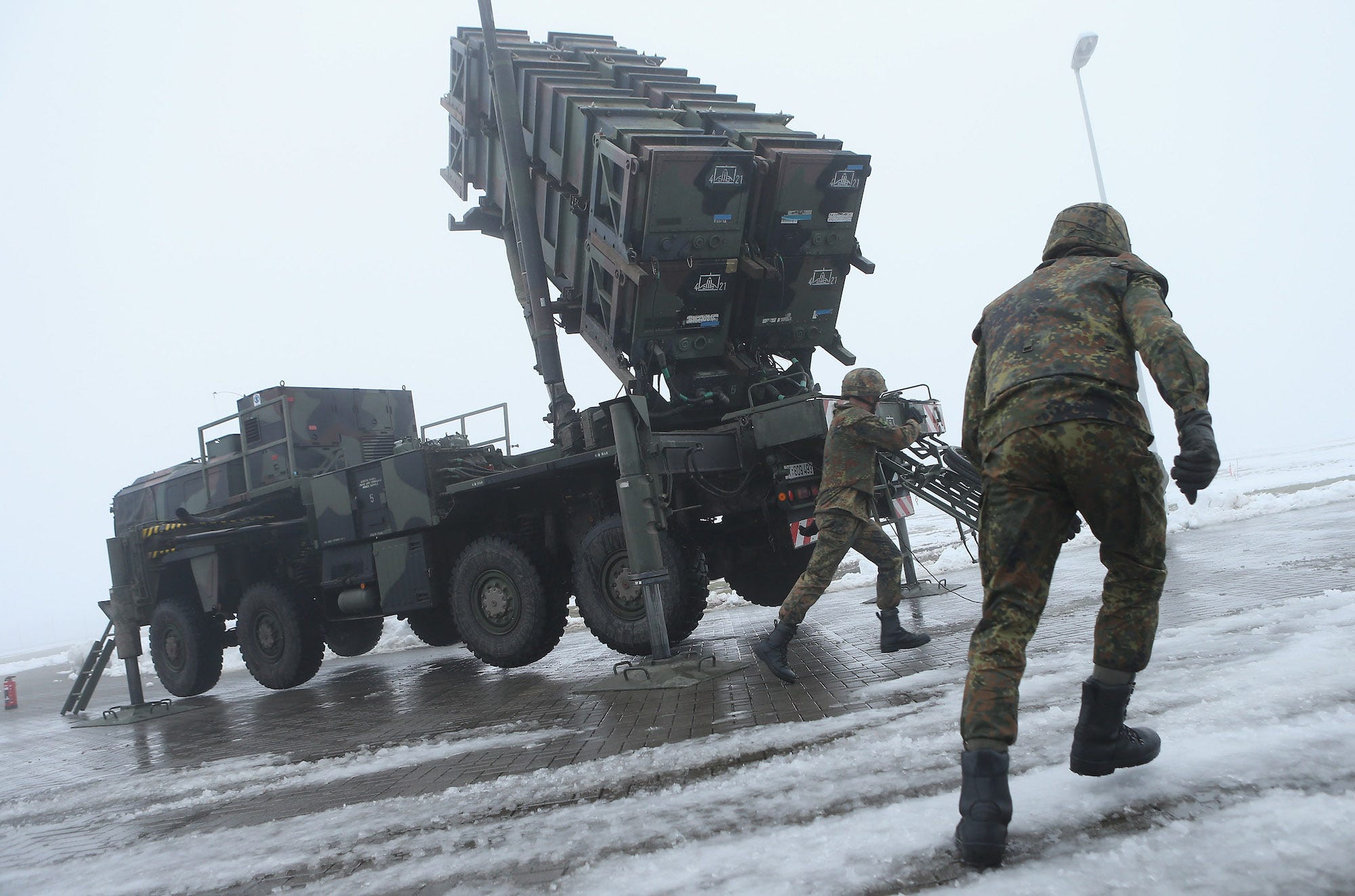 Duitse soldaten bereiden een Patriot raketlanceersysteem voor op besneeuwde grond en tegen een grijze lucht