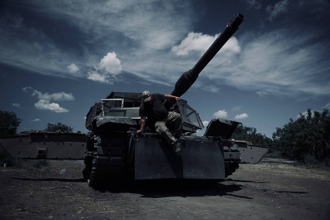 Een soldaat die van de voorkant van een M1A1 Abrams tank naar beneden klimt.