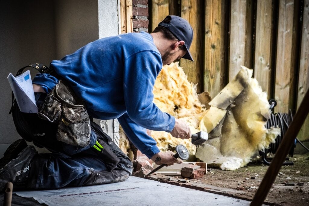 Een huiseigenaar klust aan zijn huis en brengt glaswol aan om de muren te isoleren.