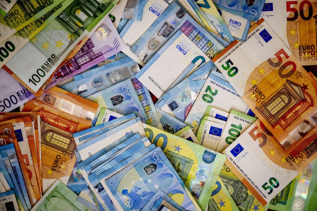 Eurbiljetten van verschillende bedragen bijelkaar op een tafel illustreren de geldstromen van banken naar bedrijfsleven.
